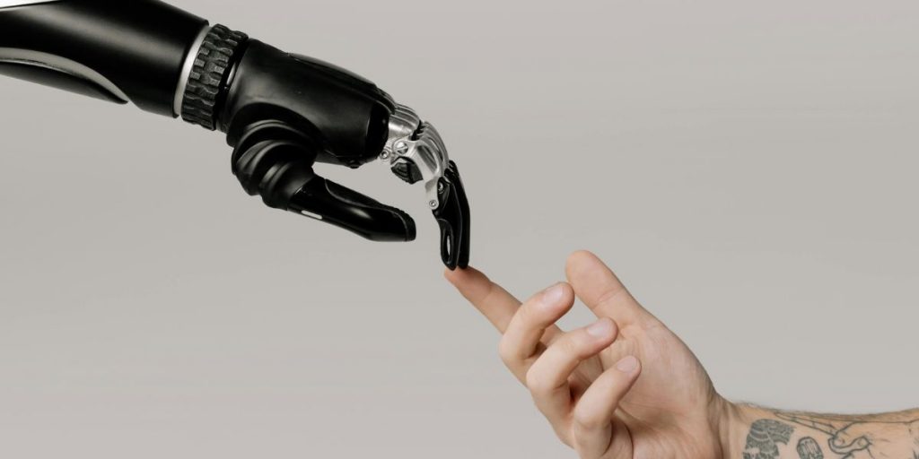 A robotic hand and a human hand touching fingertips, symbolizing the future of business internet with the integration of artificial intelligence and automation in reshaping business processes and enhancing decision-making.