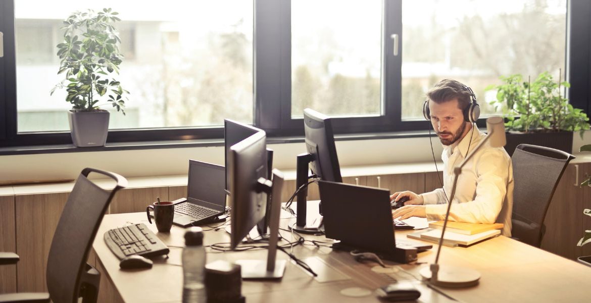 Business professional using a computer and wearing headphones in a modern office, showcasing 3CX CRM integration for streamlined communication.