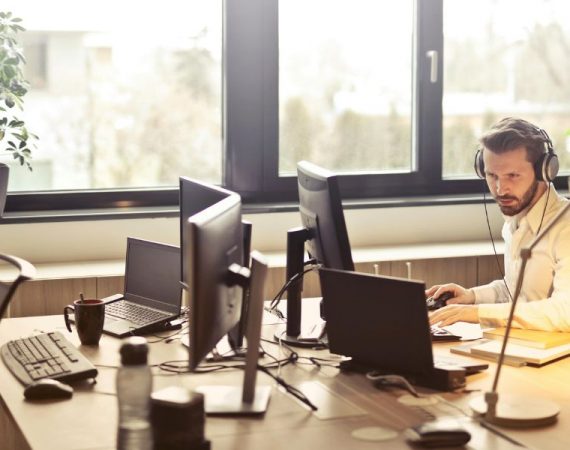 Business professional using a computer and wearing headphones in a modern office, showcasing 3CX CRM integration for streamlined communication.