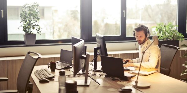 Business professional using a computer and wearing headphones in a modern office, showcasing 3CX CRM integration for streamlined communication.